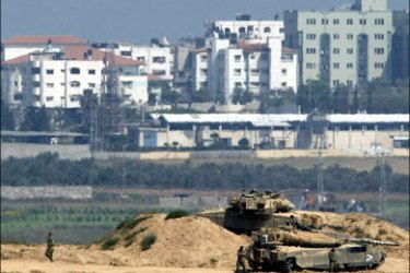 afp : Israeli tanks are stationed next to a watchtower along the border with the Gaza Strip on June 8, 2009. At least four Palestinian militants were killed in a gunbattle with Israeli