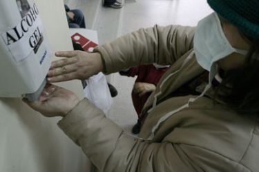 A woman washes her hands with disinfectant while waiting to be seen by a doctor at a hospital in Santiago on June 18, 2009. Chile has confirmed a fourth death from the H1N1
