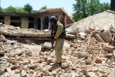 afp : A Pakistani security officer stands on the rubble of houses destroyed during a military operation against Taliban militants in Sultanwas village in Buner district on June 19,