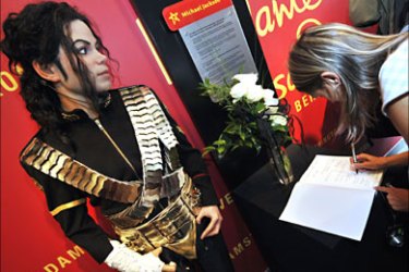 A German woman signs a condolence book next to a wax figure of US pop icon Michael Jackson, at Berlin's Madame Tussaud's wax museum June 26, 2009.