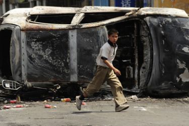 A boy runs in front of the burnt wreck of a car in a street in Urumqi in China's far west Xinjiang province on July 6, 2009. China said on July 6 at least 140 people were killed and over 800 injured when Muslim Uighurs rioted in its restive Xinjiang region in some of the deadliest ethnic unrest to have hit the country for decades