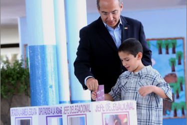 Handout picture released by the Mexican Presidency showing Mexican President Felipe Calderon casting his vote with his son Juan Pablo during the country's midterm congressional elections, in Mexico City on July 5, 2009. Some 77 million Mexicans are eligible to vote in the elections to choose who will occupy 500 seats in the Chamber of Deputies, six governorships and 568 mayoralties around the country