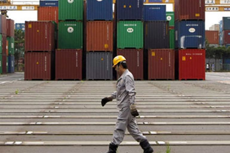 r : A worker walks in a container area at a port in Tokyo July 23, 2009. Japan's annual export slide slowed in June from May, trade data showed on Thursday, suggesting that