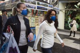 r : Women wearing protective masks to avoid getting the H1N1 flu virus walk by on a Buenos Aires street, July 7, 2009. Argentines are questioning the government's handling of an