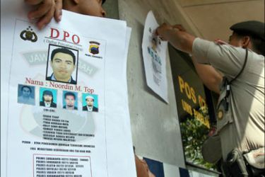 afp : Indonesian policemen put up pamphlets featuring Malaysian Noordin M. Top as a wanted person in Solo on July 23, 2009. Indonesian President Susilo Bambang Yudhoyono
