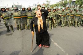 afp : Chinese riot police watch a Muslim ethnic Uighur woman protest in Urumqi in China's far west Xinjiang province on July 7, 2009 following a third day of unrest.