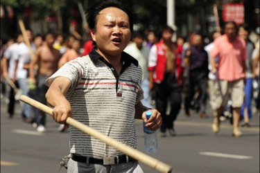 afp : A Han Chinese man waves a stick at a photographer to stop him taking pictures as thousands of Chinese take to the streets in Urumqi in China's far west Xinjiang province on