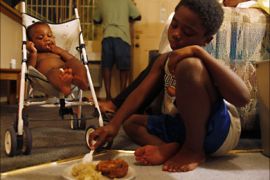 Javonte Miles, 10, sits on the floor of the motel room his family is living in and shares his dinner with his cousin, Keziah Bradley, (L) as his uncle Frederick Wilson