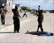 قوات حكومية تحيط بجثة في أحد شوارع مقديشو (الجزيرة)