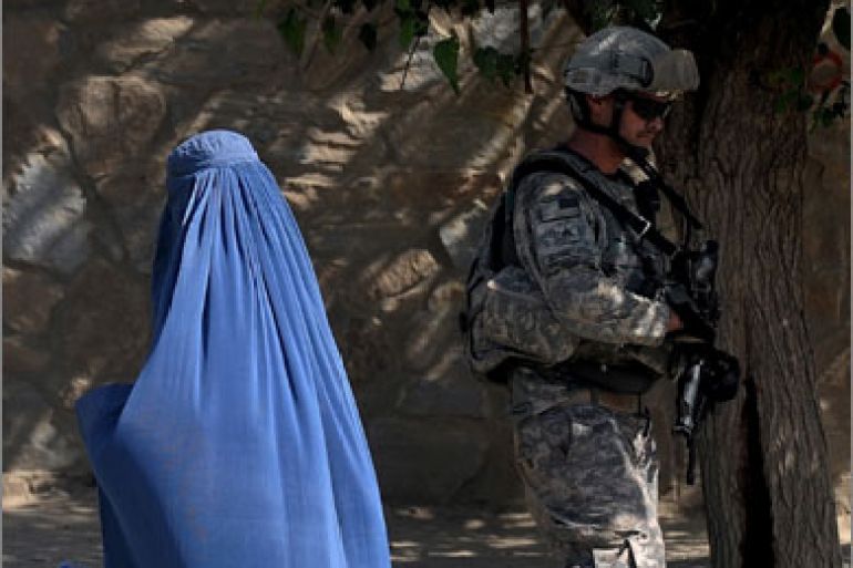 An Afghan woman (L) wearing a burqa walks past a US soldier from the 2nd Platoon Alpha 3-71 cavalry during a patrol mission in the Baraki Barak district of Logar Province on August 16, 2009
