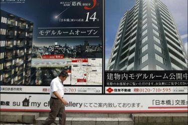 r : A man walks past an advertisement board of a real estate company in Tokyo August 14, 2009. REUTERS/Kim Kyung-Hoon (JAPAN BUSINESS)