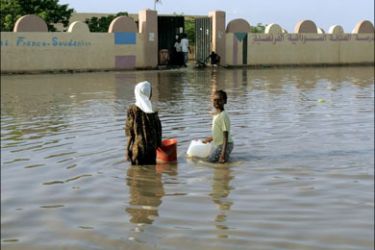 afp : A Sudanese woman and a girl stand amid a flooded road following heavy rain in southern Khartoum on August 29, 2009. AFP PHOTO/ASHRAF SHAZLY