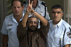 Marwan Barghouthi, a leader of the Palestinian uprising, raises his handcuffed hands as he leaves Tel Aviv District Court in this September 29, 2003