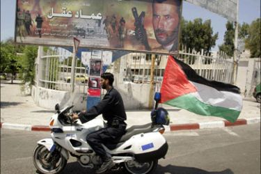 r : A Hamas policeman rides a motorcycle past a billboard promoting a film titled "Imad Aqel" in Gaza City August 3, 2009. "Imad Aqel", which had its premiere on Saturday, is the