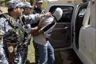 r : Iraqi policemen apprehend one of the two suspects in Baghdad August 25, 2009. Two suspects have been arrested after ransacking the house in an attack that left a