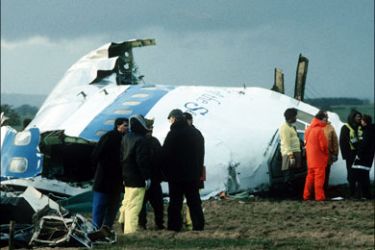 r : Scottish rescue workers and crash investigators search the area around the cockpit of Pan Am flight 103 in a farmer's field east of Lockerbie, Scotland, after a mid-air bombing