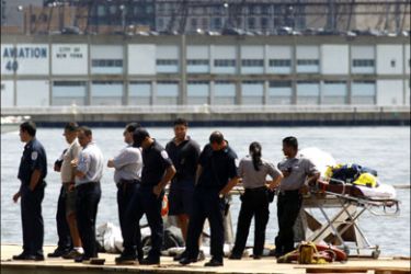 r : Emergency workers stand on a pier near the site of a crash between a helicopter and an aircraft over the Hudson River, between New York and Hoboken, New Jersey, August