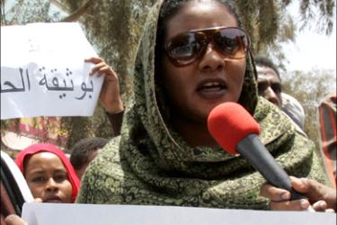 r : Lubna Hussein, a former journalist and U.N. press officer, carries a placard that reads "know your rights" as she addresses the media after her trial in Sudan's capital