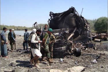 Members of the security forces walk at the site of a NATO airstrike which destroyed two fuel tankers hijacked by the Taliban in northern Kunduz on September 4, 2009.