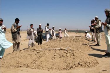 r : Afghan villagers pray over the graves of their relatives, who died in Friday's air strike, near their village of Yaqoubi in the northern Afghan city of Kunduz September 5, 2009.