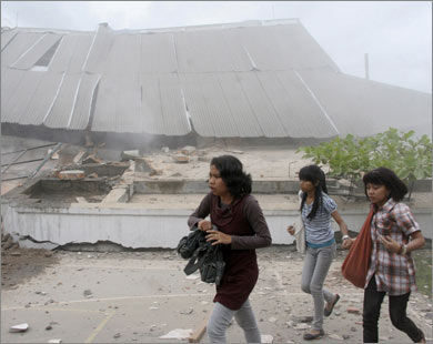 طالبات يمررن هاربات أمام مبنى جامعي هدمه زلزال بادنغ (رويترز)