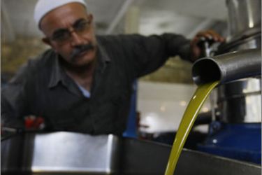 A Lebanese Druze man inpects his olive oil at a mill in the village of Baakline, southeast of Beirut on October 16, 2009.