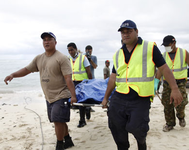 رجال شرطة يحملون جثة ضحية أغرقها تسونامي بماتفاي جنوب غرب ساموا (رويترز)