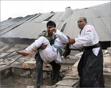 رجال إنقاذ يحملون جريحا قبالة مبنى جامعي دمره زلزال بادنغ (رويترز)