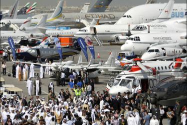 afp : Emirati officials and visitors walk past planes during the opening ceremony of the Dubai Airshow at the airport of the Gulf emirate on November 15, 2009. The Dubai Airshow