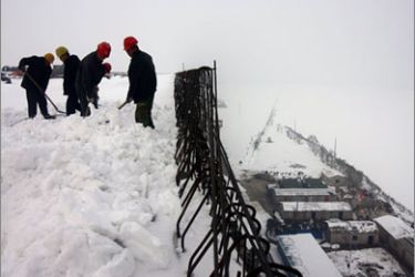 Chinese workers continue work on a bridge construction project after a snowstorm hit the city of Zhengzhou in central China's Henan province