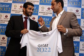 Hassan Abdulla Al Thawadi (L), the Chief Executive Officer of Qatar World Cup 2022 bid committee, and former Saudi Arabian player Sami Al Jaber (R) hold a Qatar 2022 T-Shirt