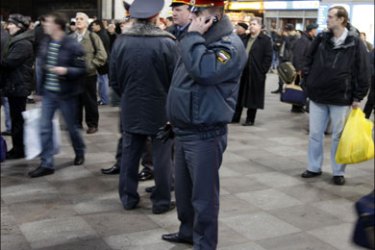 r : A police officer speaks on the phone while passengers wait as train services were suspended at Moskovsky train station in St. Petersburg November 28, 2009. Twenty-two