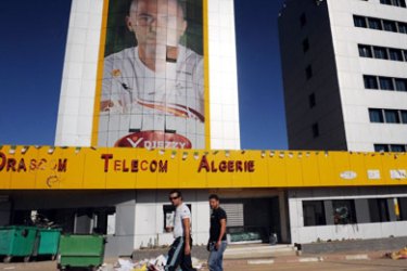 F/Algerian men pass by the damaged main offices of mobile telephone company Djeezy, part of the Egyptian telecommunications group Orascom, on November 16, 2009 in Algiers.