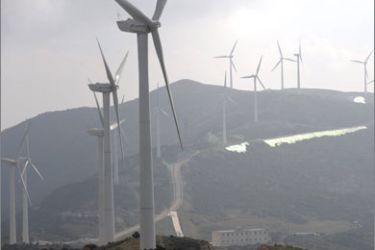 A man (lower) walks near a wind turbine complex on the Zhemo Mountain in the outskirts of Dali, in China's southwestern province of Yunnan on November 5, 2009