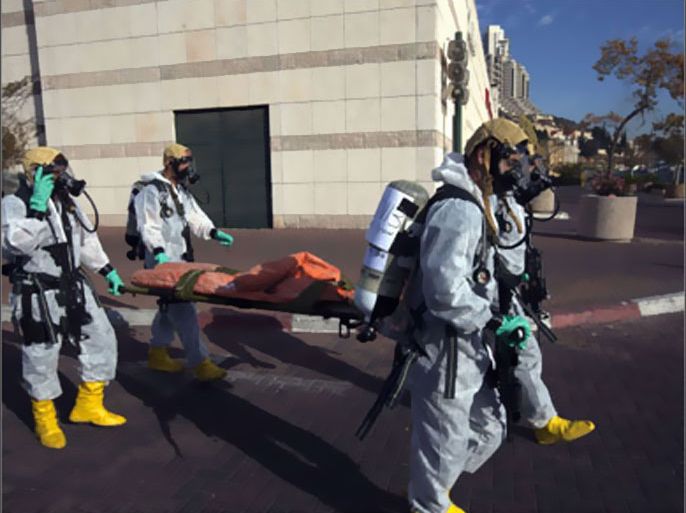 Israeli policemen wearing protective masks and suits evacuate an inflatable doll, representing a victim, during a chemical warfare drill simulating an attack on a mall in Jerusalem on November 15, 2009