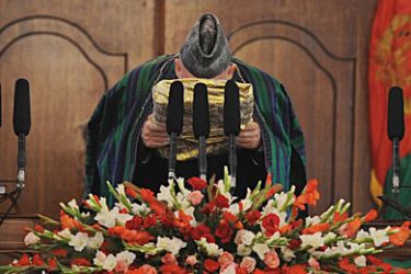 Afghan President Hamid Karzai kisses a large copy the Koran during his swearing in ceremony as the country's president for another five years at the Presidential Palace in Kabul on November 19, 2009.