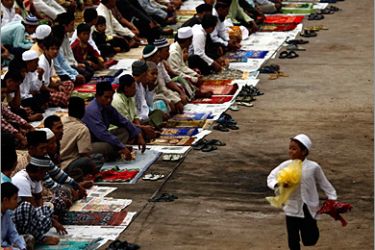 A boy runs past Muslims attending Eid al-Adha prayers at a port in Jakarta November 27, 2009. Muslims around the world celebrate Eid al-Adha to mark the end of the haj by