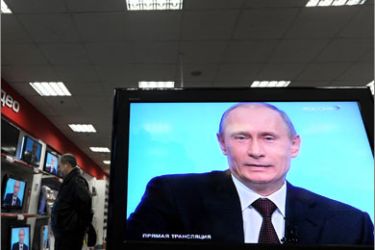Russian Prime Minister Vladimir Putin is seen speaking on television sets at an electronics store during his annual televised phone-in show in Moscow
