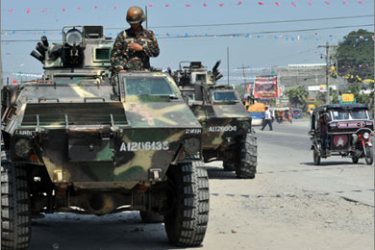 A soldier stands atop a parked armored personnel carrier on a road in Tacurong, in Sultan Kudarat province next to the southern Philippine province of Maguindanao