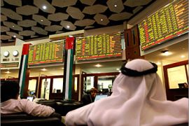 REUTERS /Investors look at stock exchange information at the Dubai Financial Market December 9, 2009. Concern over debts at Dubai's utility provider and losses at Nakheel, builder of the
