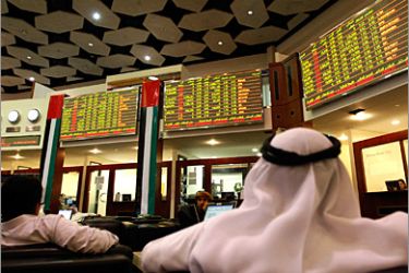 REUTERS /Investors look at stock exchange information at the Dubai Financial Market December 9, 2009. Concern over debts at Dubai's utility provider and losses at Nakheel, builder of the