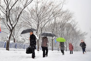 Pedestrians walk along a snow-covered road in downtown Seoul on January 4, 2010. South Korean weather office issued a heavy snow alert for Seoul and surrounding areas, where just over 17 centimetres (almost seven inches) of snow fell in just four hours.