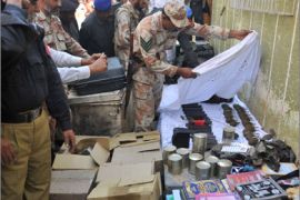 Pakistani security officials inspect weapons and explosives material recovered from a collapsed house following an explosion in Karachi on January 8, 2010.