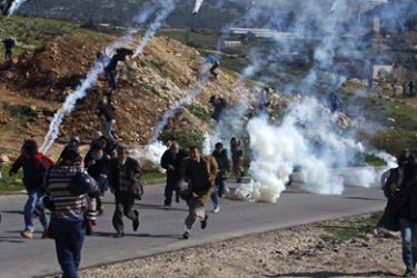 Palestinian protesters and international activists run away from tear gas fired by Israeli troops during a protest in the West Bank village of Nabi Saleh near Ramallah January 29, 2010. Israeli forces used tear gas to disperse the violent protest over a land dispute with Jewish settlers in the area.