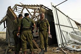 r : Israeli soldiers survey the damage to a warehouse after a rocket fired by Palestinian militants in Gaza landed in Kibbutz Nirim, outside the Gaza Strip March 11, 2010.