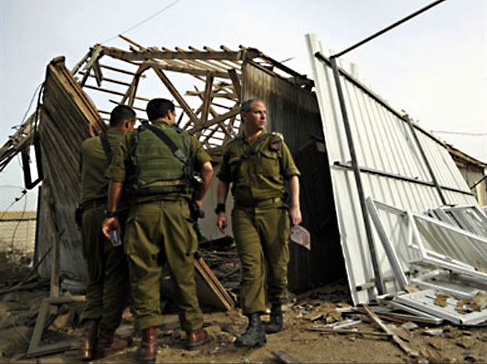 r : Israeli soldiers survey the damage to a warehouse after a rocket fired by Palestinian militants in Gaza landed in Kibbutz Nirim, outside the Gaza Strip March 11, 2010.