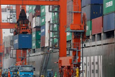 r_Workers load a cargo container on a truck at a pier in Tokyo March 24, 2010. Japan's exports fell in February from the previous month in a sign that a rebound in external