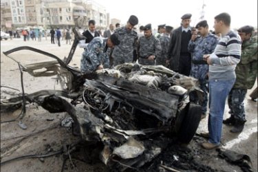 r : Iraqi policemen examine the remains of a vehicle used in a bomb attack in Najaf, 160 km (100 miles) south of Baghdad, March 6, 2010. A car bomb exploded in Iraq's holy city of
