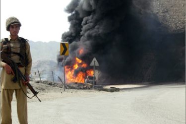 A Pakistani paramilitary soldier stands near a burning NATO oil supply tanker after an explosion in Khyber on April 7, 2010. Taliban militants bombed a tanker used to supply fuel to NATO forces in Afghanistan on