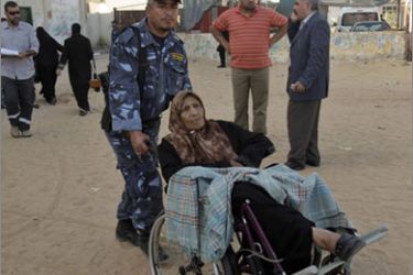 A member of Hamas' security force helps a Palestinian woman cross the Rafah border in the southern Gaza Strip May 15, 2010.The Rafah crossing